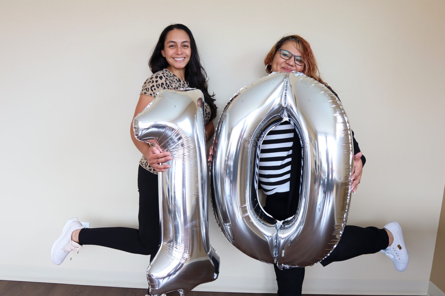 Two women holding up balloon 10